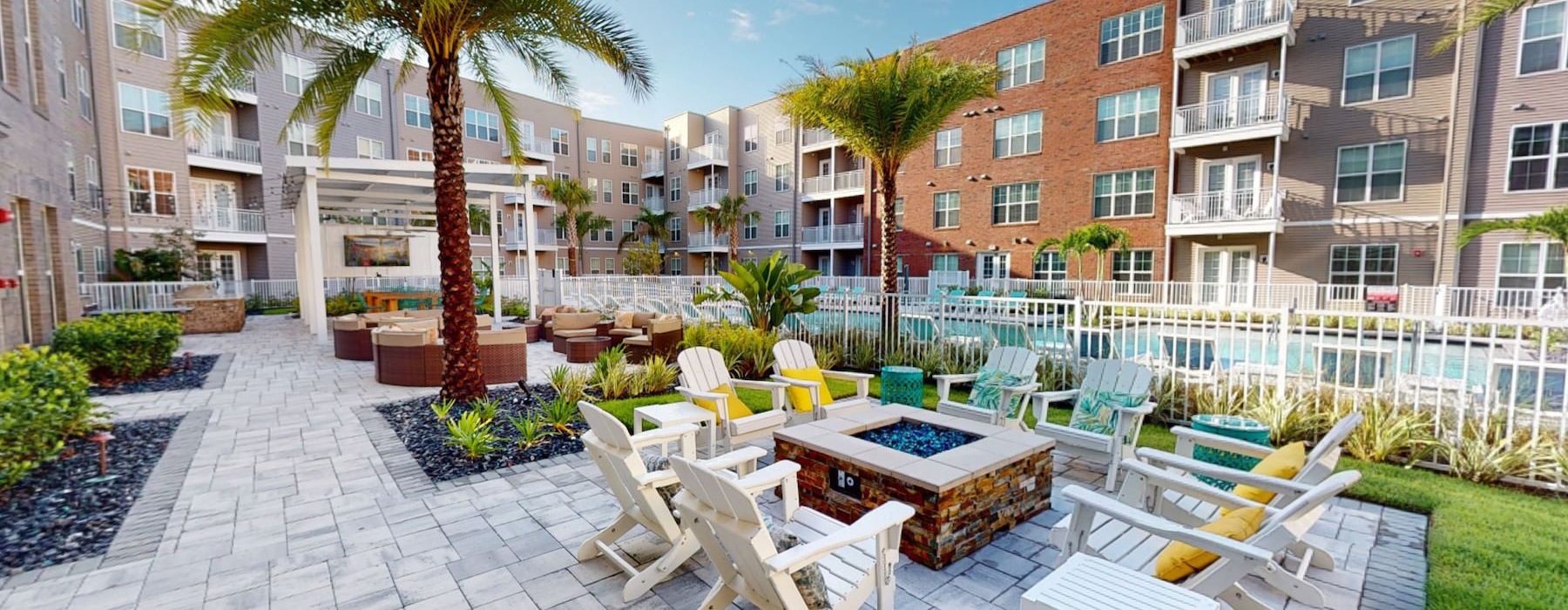 a courtyard with a firepit and chairs next to a pool